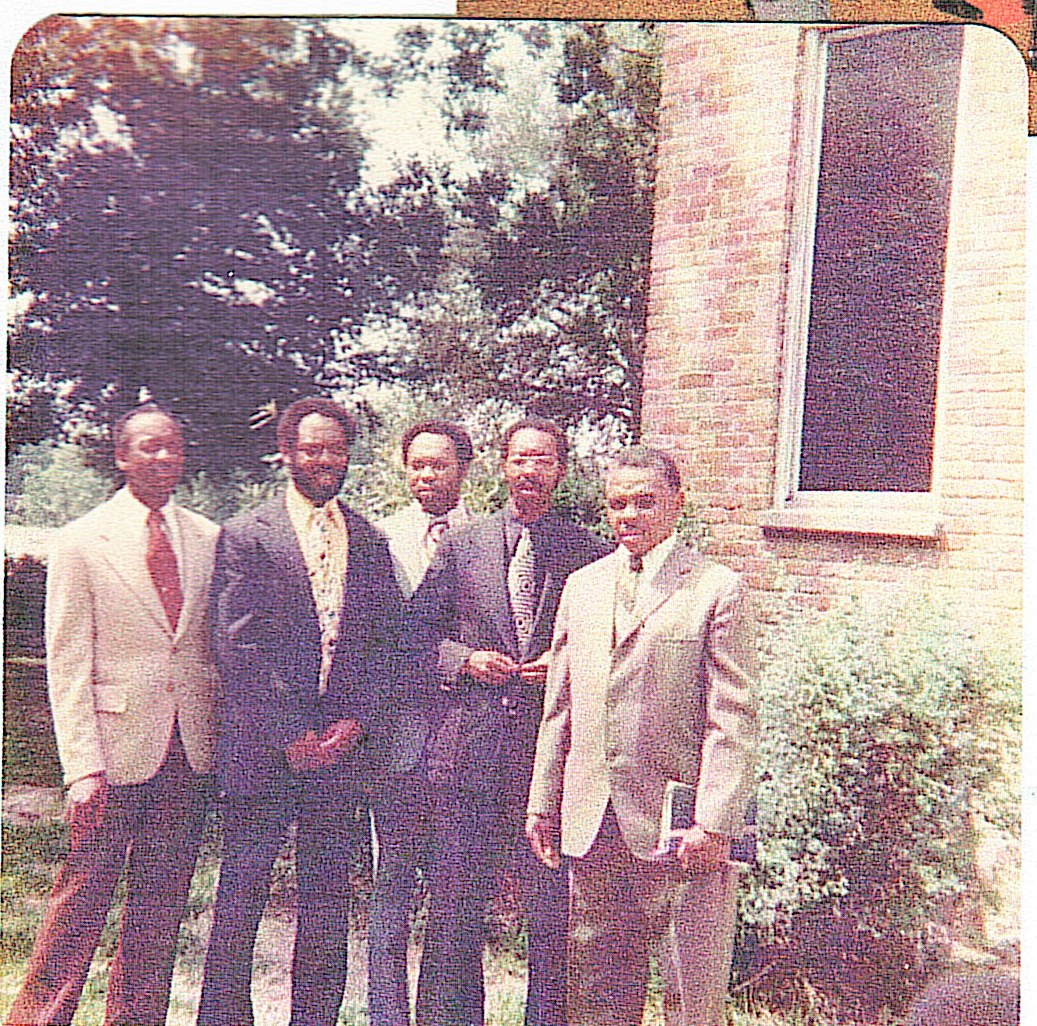 Historical family photograph of men in suits outside a building